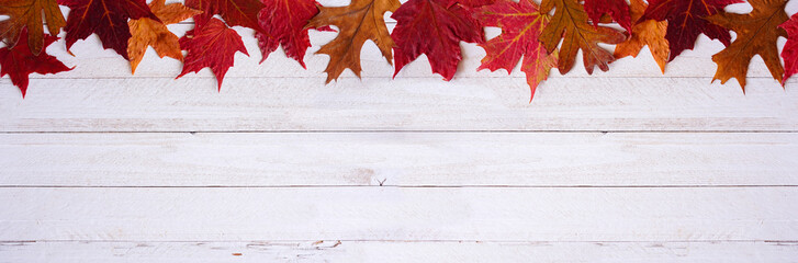 Poster - Colorful autumn leaves top border over a white wood banner background. Above view with copy space.