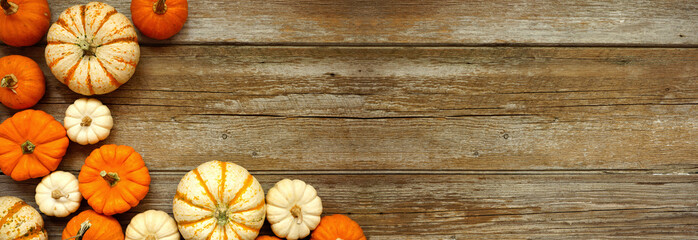 Poster - Fall corner border of orange and white pumpkins over a rustic wood banner background. Above view with copy space.