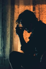 Poster - A man is sitting in a dark room with a glass of beer in his hand. He is in a state of deep thought or contemplation