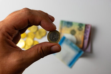 Wall Mural - Euro coins in a hand and banknotes on a table