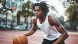 © cvetikmart - Intense young man with dreadlocks dribbling on a basketball court, wearing athletic gear and concentrating on the hoop, with the surrounding neighborhood visible