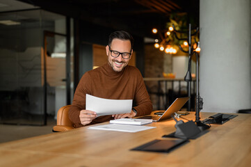 Confident young businessman auditing revenue report and planning budget while working at desk in office