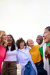 © CarlosBarquero - Vertical. Group of multiracial young only women standing embracing in circle laughing outdoor. Gen z female community friends people hugging together having fun enjoying leisure time. Copy space up