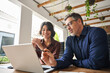 © insta_photos - Two happy busy professionals business team people working together using laptop computer. Male executive manager explaining corporate online project plan to female partner sitting at office desk.