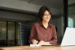 © insta_photos - Busy happy young Hispanic business woman company owner ceo working in office using laptop writing notes. Female professional executive manager in her 30s using computer, elearning at workplace.