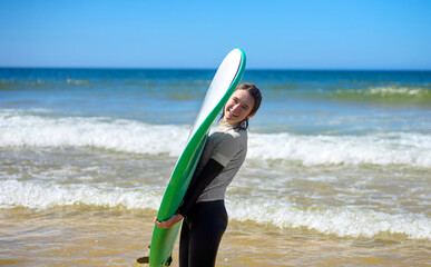 Surfer. Teenage girl learning to surf on foam in the ocean. First surfing lesson. Amateur surfer. Surfing training. Photo for surfing school advertising on social media.