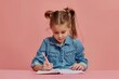 © Ева Поликарпова - A young girl sits at a table with pencils and paper, engaged in creative writing
