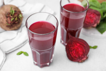 Canvas Print - Fresh beet juice in glasses and ripe vegetables on light table, closeup