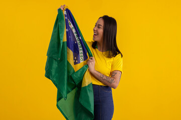 Young beautiful woman wearing yellow shirt and holding Brazil flag in studio shot with various expressions of feelings