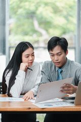 Wall Mural - Two business professionals reviewing documents together in a bright, modern office environment.