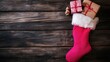 © B 7 YOU - A festive pink stocking filled with gifts on a wooden surface, evoking holiday cheer.