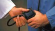 © sarana - Taking Blood Pressure: Doctor's hands wrapping a blood pressure cuff around a patient's arm and inflating it.
