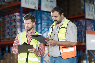 Warehouse concept. Two male warehouse worker working and checking boxes of products on shelf in warehouse. Group of two male worker at warehouse