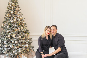 winter holidays and people concept - happy couple decorating christmas tree at home