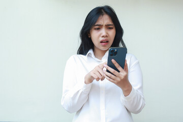 Wall Mural - shocked asian business woman manager confused scrolling social mediaon  smartphone screen wearing white suit formal shirt, read bad news, surprised sale promo online shopping standing isolated