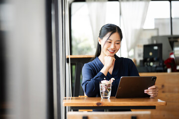 Wall Mural - beautiful asian businesswoman in the cafe, using digital tablet and smiling