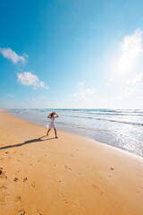 Wall Mural - happy girl in a white dress runs along the beach and enjoys her vacation. A carefree girl walks along the beach on a sunny day.