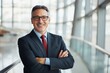 © 为轩 张 - Professional Middle-Aged Male Manager with Red Tie and Glasses Smiling in Modern Office Building.
