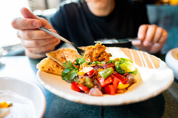 close-up of a person enjoying a vibrant, healthy meal with fresh vegetables and flatbread, perfect for culinary or lifestyle themes. The colorful dish emphasizes the concept of healthy eating.