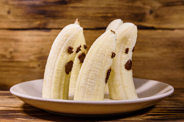 Scary banana ghosts in ceramic plate on a wooden table. Halloween concept