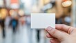 © okfoto - Dynamic marketing scene, hand holding blank business card in busy shopping crowd for branding and contact info. Ideal for marketing strategies