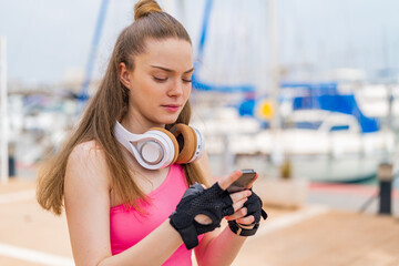 Canvas Print - Young pretty sport girl at outdoors sending a message or email with the mobile