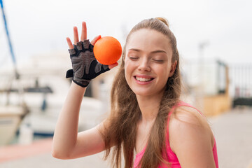 Wall Mural - Young pretty sport girl at outdoors holding an orange with happy expression