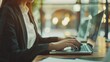 © Galib - A woman in a blazer sits at a desk, working on a laptop.