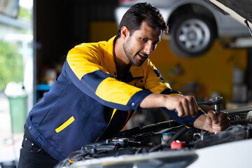 Close up mechanical hand with tools and spanner. Hispanic latin male mechanic repairs car in garage. Car maintenance and auto service garage concept