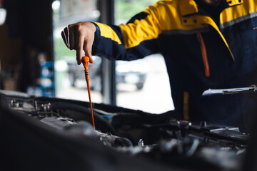 hispanic latin male mechanic repairs car in garage. Closeup hand. Auto car mechanic checking the oil level of the car engine. Car repair and maintenance