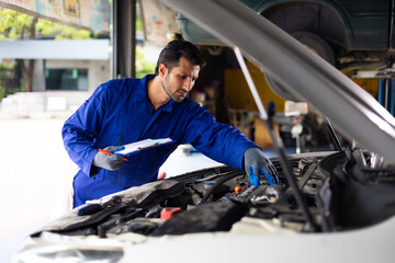 Hispanic latin man mechanic repairs car in garage. Car maintenance and auto service garage concept. Closeup hand and spanner. Insurance agent