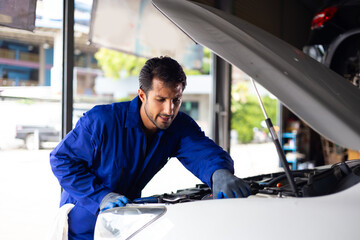 Hispanic latin man professional mechanic repairs car in garage. Car maintenance and auto service garage concept. Closeup hand and spanner