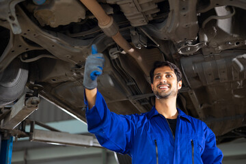 Portrait hispanic latin male mechanic repairs car in garage. Auto car mechanic professional working and checking car engine at garage. Car repair and maintenance