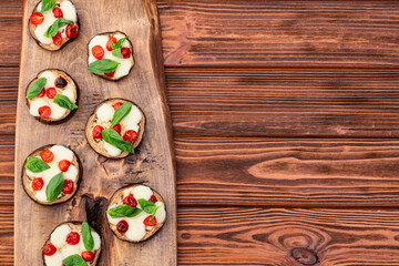 Wall Mural - Italian mini pizza . Aubergine (eggplant ) with mozzarella cheese and basil . On rustic background