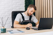 © anatoliycherkas - Caucasian business manager or mechanic sitting and writing report in front of laptop-notebook in office at car service