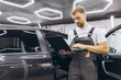 © anatoliycherkas - Young professional technician car mechanic man in grey overalls t-shirt use hold laptop pc computer make diagnostics fix problem in vehicle repair shop workshop indoor.
