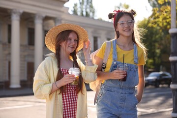 Happy teenage friends walking on city street