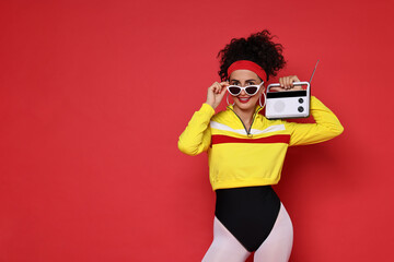 Poster - Aerobics. Woman in sportswear holding radio receiver on red background