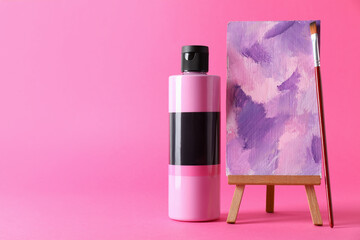 Wall Mural - Acrylic paint in bottle, small easel with abstract picture and brush on pink background, space for text