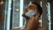 © alan - Man shaving beard at home.