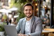 © LAJT - Smiling businessman working on laptop in outdoor cafe, concept of remote work, entrepreneurship, and modern business lifestyle