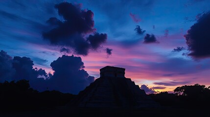 Wall Mural - A panoramic view of Chichen Itza at dusk, with the silhouette of El Castillo against the evening sky.