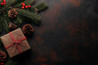 © Aisyaqilumar - Christmas background with red and dark brown colors on an old texture, leaving space for text. Flat lay of a top view of Christmas decorations, including a present box on a textured surface.