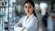 © KYR - Portrait of a confident Asian female researcher with arms crossed, working in a modern lab and looking at the camera with determination.