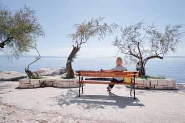 Wall Mural - Woman sitting on the bench on the sea promenade