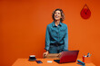 © Jacob Lund - Digital marketer smiling confidently while working on laptop indoors in monochromatic orange set.