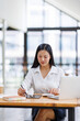 © David - Asian Businesswoman Using laptop computer and working at office with calculator document on desk, doing planning analyzing the financial report, business plan investment, finance analysis concept.