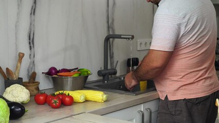 Wall Mural - Man is washing corn at the kitchen