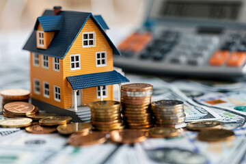  Real estate investment and savings strategy concept with a model house surrounded by stacks of coins on financial documents.