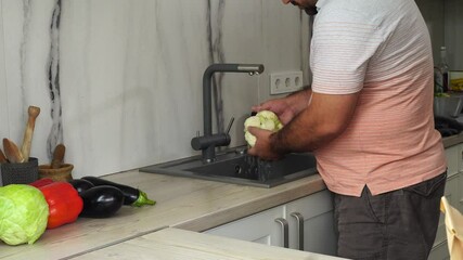 Wall Mural - Man is washing cauliflower under the tap in the kitchen